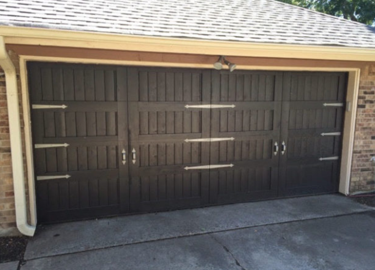 Modified black sports car parked outside an urban garage with industrial equipment nearby.